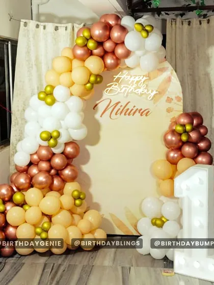 A beautiful first birthday setup in rose gold, peach, and white. The arched backdrop and light-up number '1' create an elegant and celebratory atmosphere.