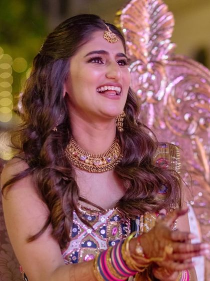 A happy bride is the best accessory. This close-up shows how the heirloom gold jewelry perfectly complemented the tones in her vibrant sangeet outfit.