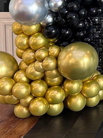The base of a balloon column made of gold and silver chrome balloons. This combination creates a striking and elegant look for any celebration.