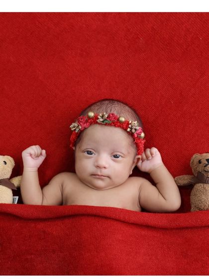 An adorable awake moment captured on a simple red background. We love these moments of connection when the baby looks directly into the lens.