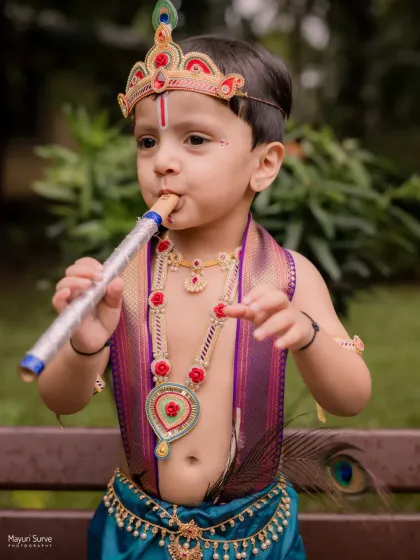 Incorporating props like a flute adds a playful and authentic touch to themed baby photoshoots. This little one was completely absorbed in his role as Krishna.