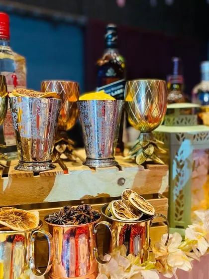 The rich textures and colors of the Gatsby theme. This shot highlights the metallic pineapple-stemmed goblets and copper mugs, filled with star anise and dried citrus, ready for crafting exquisite 1920s-inspired cocktails.