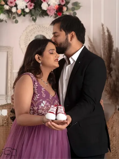 A tender kiss on the forehead and the tiny baby shoes make this a heartwarming and classic maternity photo.