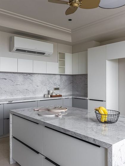 The Chiripal Residence in Ahmedabad features a bright and airy kitchen with white and grey Uno Laminate cabinets. The Brazilian granite countertop and backsplash add a touch of natural luxury.