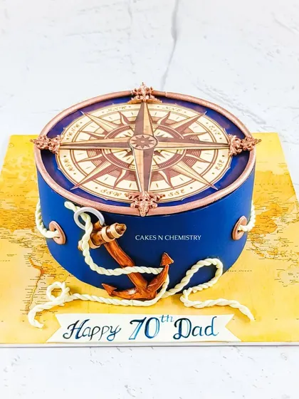 A nautical-themed cake perfect for a seasoned traveler. The design features a detailed compass on top and a fully hand-modelled anchor, all set against a world map base.