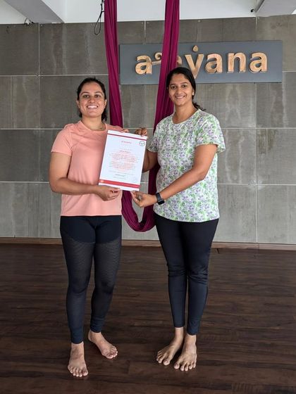 An instructor congratulates a student on her successful completion of the 30-hour aerial yoga TTC.