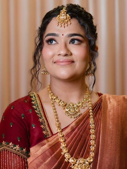 A thoughtful and elegant pose, showcasing the soft eye makeup and the beautiful details of her temple jewelry.
