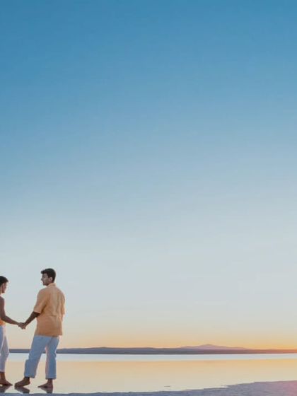 A serene, minimalist shot of a couple holding hands against a vast, clear blue sky on a Turkish beach. The simplicity of the composition emphasizes their connection and the peacefulness of the moment.