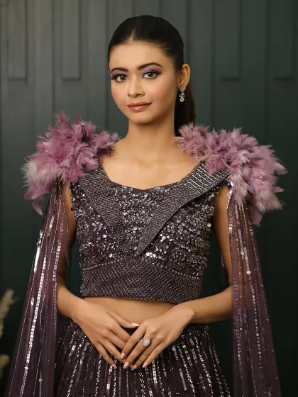 A full view of this unique and dramatic cocktail ensemble. The bold purple eye makeup perfectly picks up the tones in the feathered shoulders of her outfit.