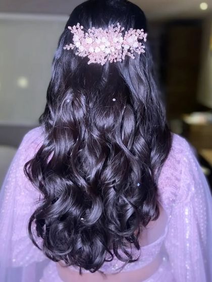 For this reception look, I created soft waves and adorned them with a beautiful pink floral hairpiece and scattered pearls for a touch of magic.