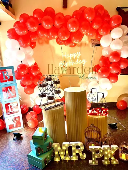 A heart-shaped balloon frame in red and white for a romantic surprise at home. The setup includes 'BABY' blocks and other fun props.