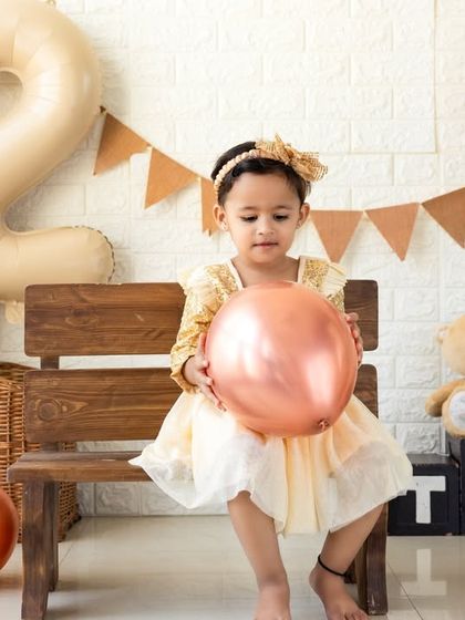 One of the twins holding a balloon, looking thoughtful. I work patiently with young children to capture a range of moods and expressions.