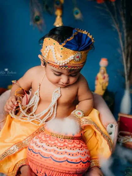 Our little Krishna is caught in the act, reaching for his pot of butter. I love creating interactive setups like this that allow for natural, story-driven moments during a themed baby photoshoot.