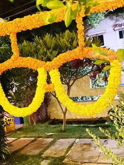 An entrance arch made entirely of marigold garlands, including a creative spectacle design. This shows how I can add a bit of fun and personality to traditional decor.