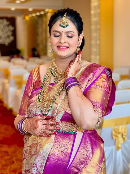 A candid moment showing the beautiful details of the makeup and jewelry. The emeralds in her jewelry are subtly picked up in her makeup for a cohesive look.