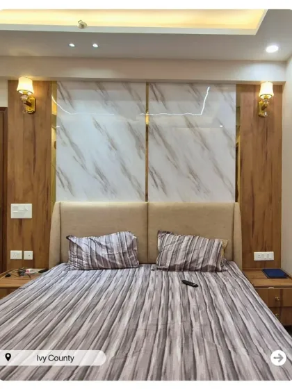 This bedroom combines wood paneling with white marble-finish slabs on the accent wall. The warm sconce lighting creates a cozy and luxurious feel.