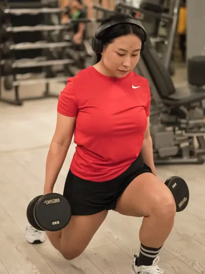 Dumbbell lunges are a versatile exercise for toning the legs and glutes, as demonstrated by this focused member.