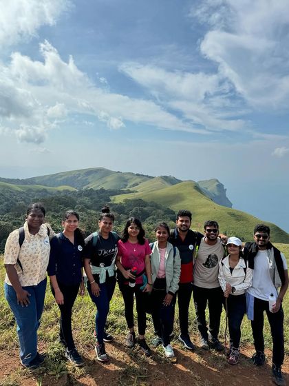 A group of friends enjoying the spectacular views from the Bandaje trek trail. The clear skies offer a glimpse of the vastness of the Western Ghats.