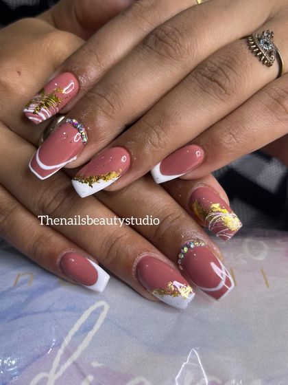 A beautiful and intricate birthday nail set. It features a modern French manicure with gold foil, white swirls, and a delicate rhinestone placement at the cuticle.
