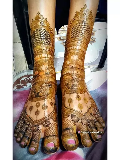 The final stained result of a heavy bridal foot mehandi. The design includes hanging jhumki (earring) motifs and dense patterns covering the entire foot and ankle.