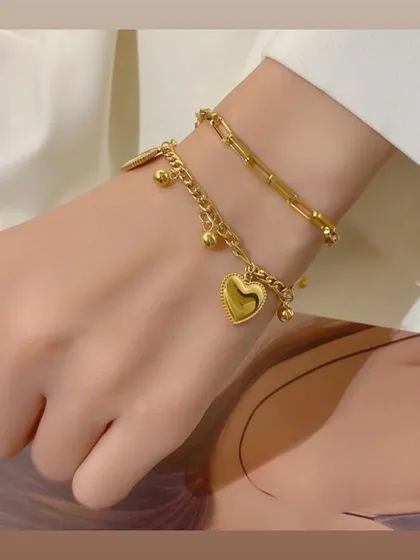 This is one of my favorite bracelets for stacking. It features a layered design with a paperclip chain and a second chain with small beads, finished with a beautiful heart charm.