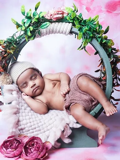 An adorable shot of an awake baby relaxing in a round floral hoop prop. This pose is great for babies who are calm and observant.