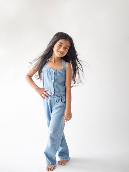A confident and cool pose from this six-year-old in a simple denim jumpsuit. The clean white background makes her personality pop.