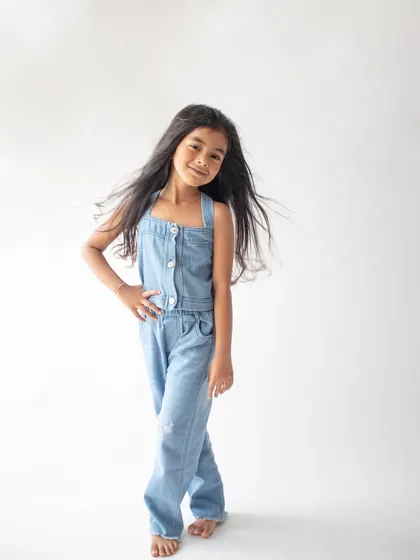 A confident and cool pose from this six-year-old in a simple denim jumpsuit. The clean white background makes her personality pop.