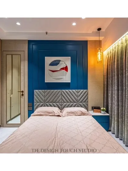 A close-up of the bed and the detailed accent wall. The combination of the bold blue color, textured headboard, and modern art creates a personalized and stylish retreat.