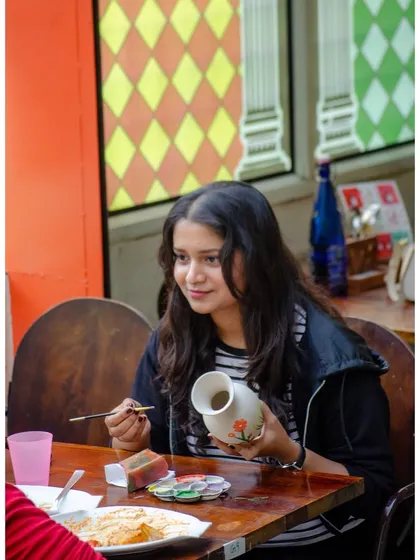 A guest enjoying a quiet moment of creativity, adding delicate floral designs to a vase. Our cafe provides a peaceful setting to focus on your art while you enjoy a meal.