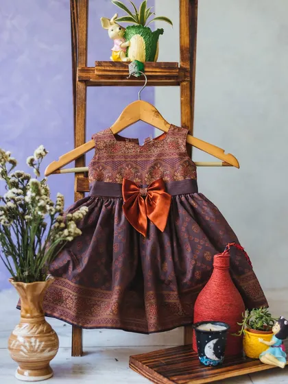 For a touch of unique flair, I love creating Indo-Western fusion pieces. This dress features a traditional brocade pattern in a modern silhouette, complete with a beautiful contrasting bow for a look that celebrates heritage with style.
