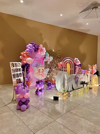 A side view of the butterfly party decorations, showing the photo collage and the depth of the setup.