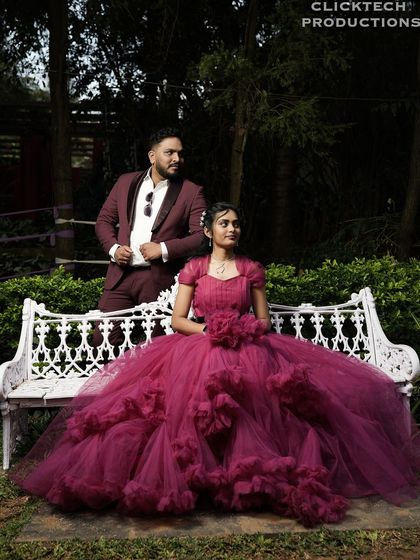 A fairy-tale moment in a garden, with the bride in a magnificent ruffled gown sitting on a bench next to her groom.