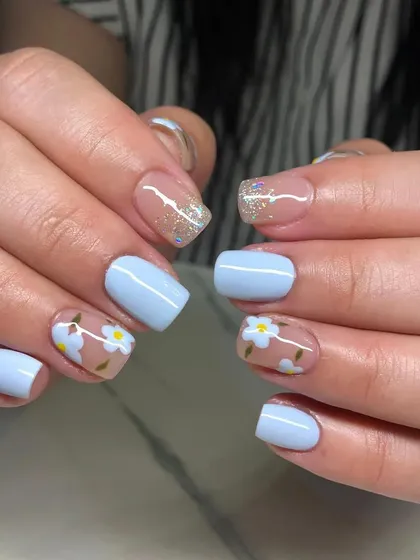 A sweet and simple design on short, square nails. This set features a light blue polish with accent nails showcasing hand-painted daisies.