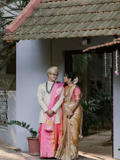 A happy couple poses in front of one of our suites, their traditional outfits popping against the simple, elegant background.