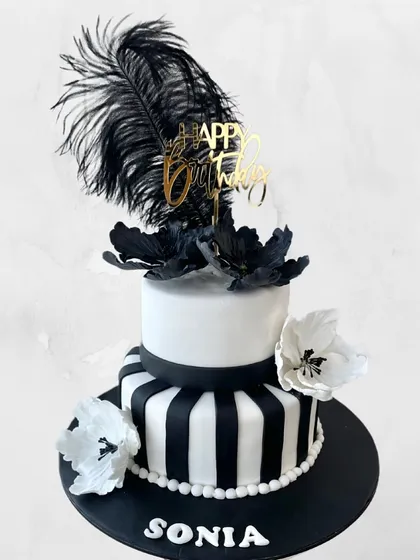 A chic black and white cake for Sonia's birthday. The design features bold stripes, elegant sugar flowers, and a dramatic black feather for a touch of Great Gatsby glamour.