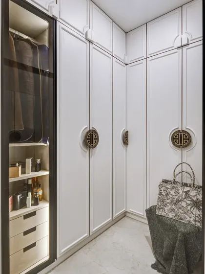 Details matter. This walk-in wardrobe features custom-designed doors with intricate handles, creating a look of bespoke luxury.