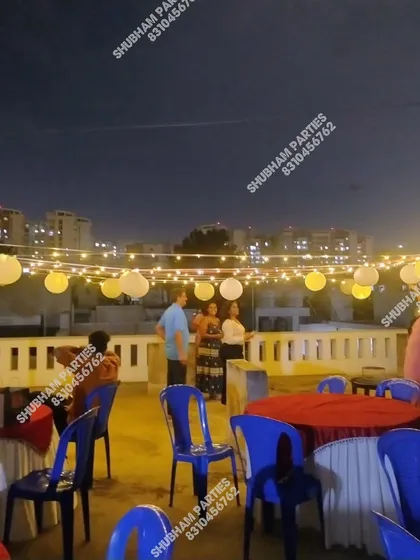 A simple and elegant rooftop party setup with string lights and paper lanterns.