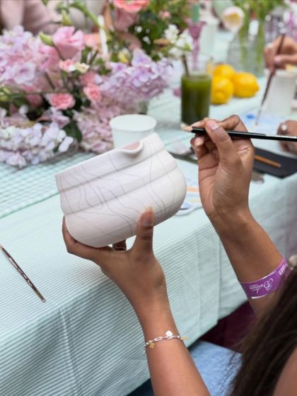 A guest at our Bastian event carefully painting their matcha bowl, surrounded by fresh flowers and good company.