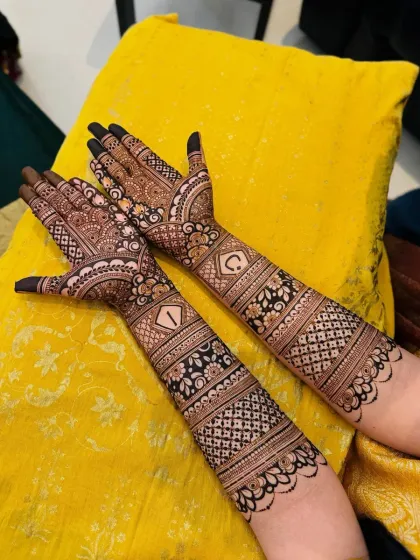 A clear shot of a bridal design with initials, set against a yellow backdrop that makes the henna pop. The symmetry and clean lines are a hallmark of my work.
