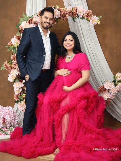 A happy and classic portrait of the expecting couple. Posed against a floral arch, this shot captures their shared excitement and the beauty of their journey together.