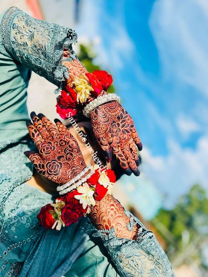 A gorgeous mehendi stain, beautifully accessorized with floral bracelets. The deep color looks stunning against the clear blue sky.