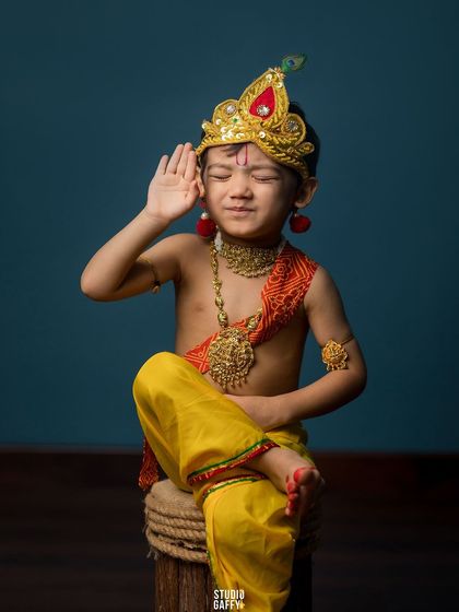 A playful moment, with little Krishna pretending to listen for something.