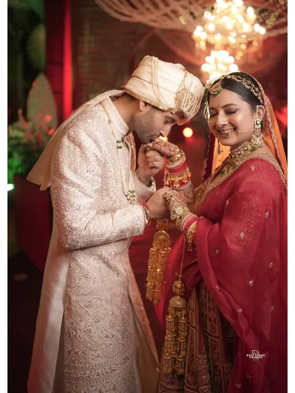 A gesture of pure love and respect. The groom gently kisses the bride's hand, a candid moment filled with chivalry and tenderness.