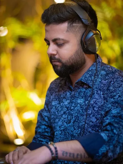 A focused shot of me at the decks, with the warm ambient light of the club in the background.