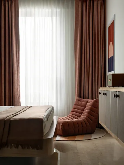 A custom-made lounger creates a cozy reading nook by the window. The console cabinet, with its textured panels and vibrant red knobs, was also designed and built by us.