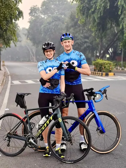 A fitness couple making a heart sign with their hands, showing their shared love for cycling.
