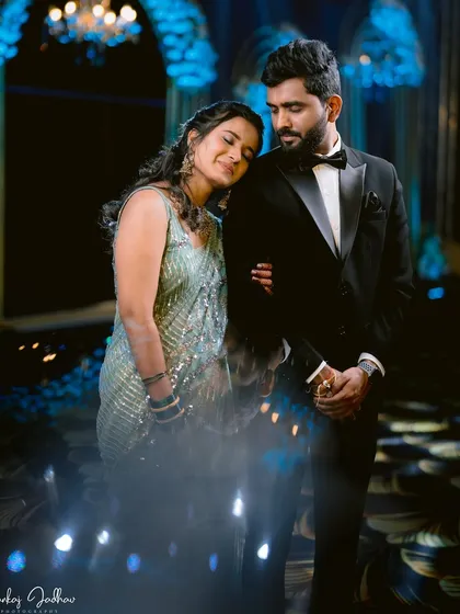 A quiet moment of peace amidst the Sangeet festivities. Ruchi rests her head on Sanket's shoulder, a beautiful, candid portrait under the dramatic blue lighting.