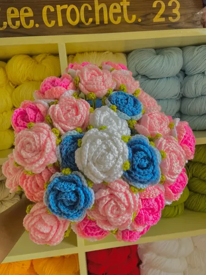 A close-up of a custom rose bouquet with pink, white, and blue flowers.
