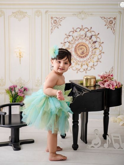 Let's play piano. This little cutie in her green and blue tutu is ready to make some music.